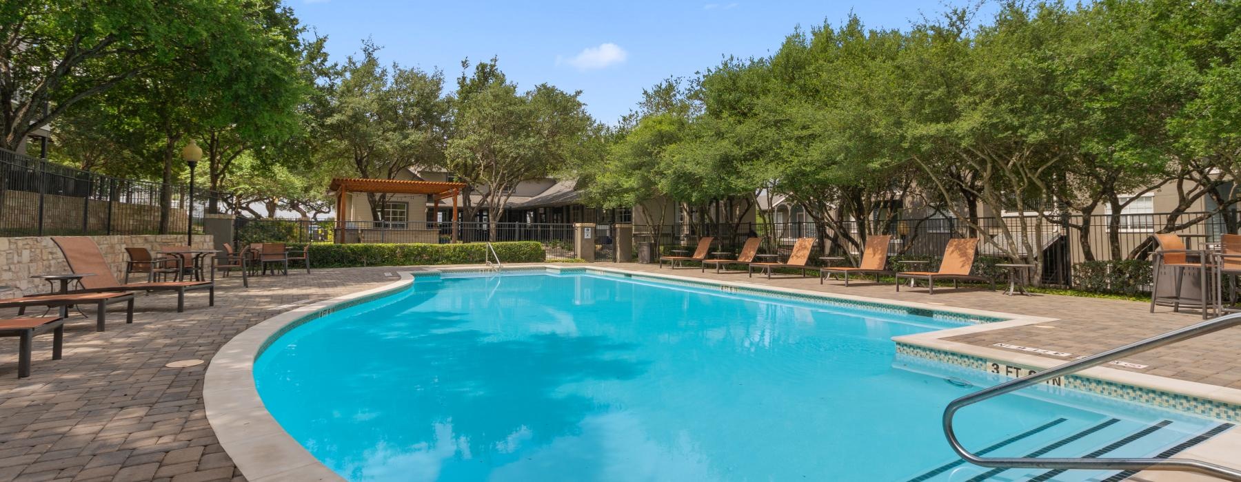 a swimming pool with trees and a building in the background